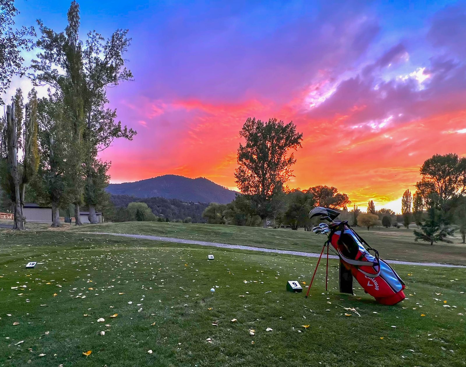 Golf bag on the fairway under a vivid sunset