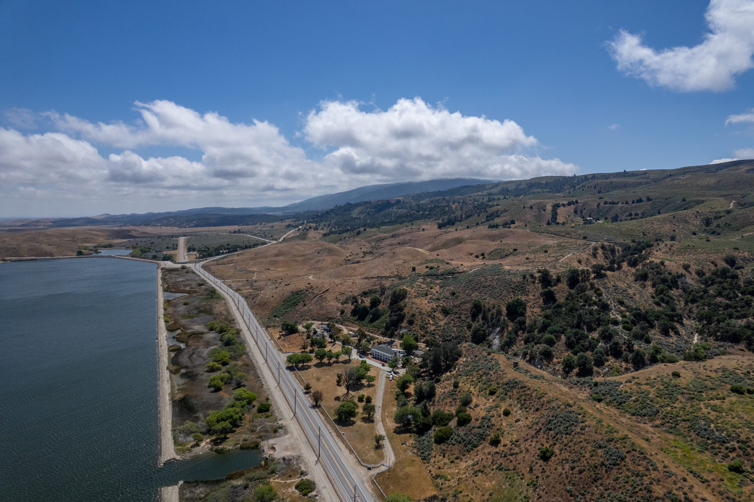 Aerial over a hillside estate, the highway and a mountain lake