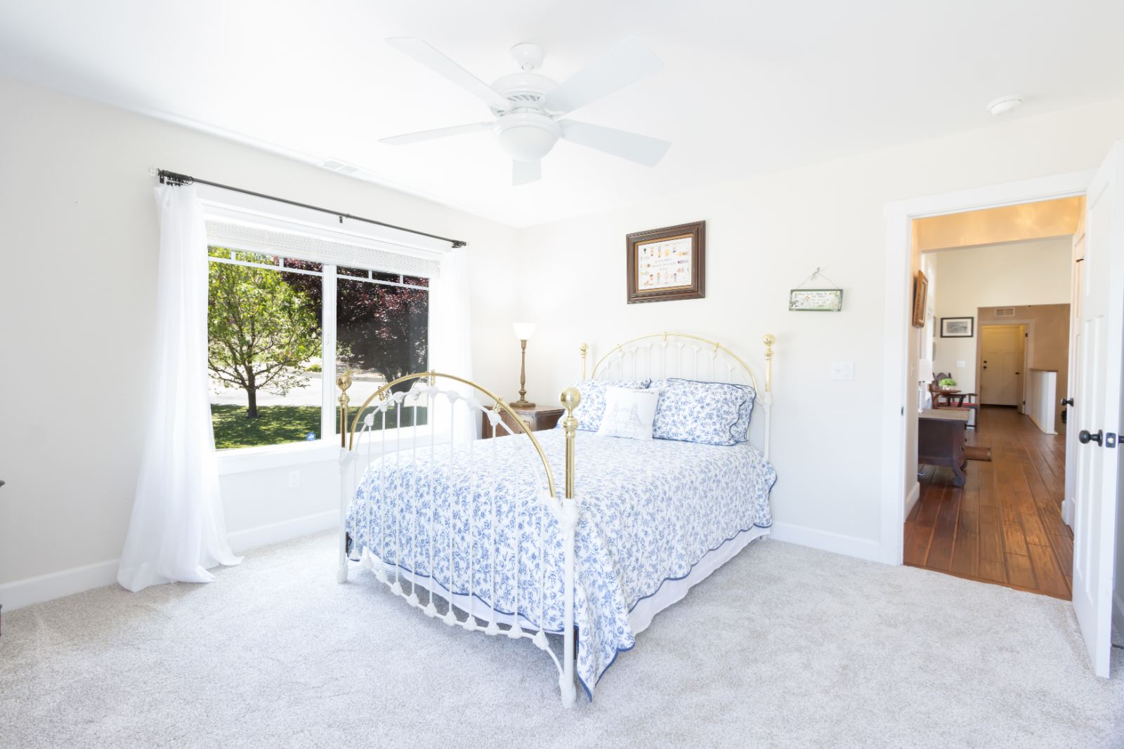 Bedroom with brass bed, garden window and hall beyond