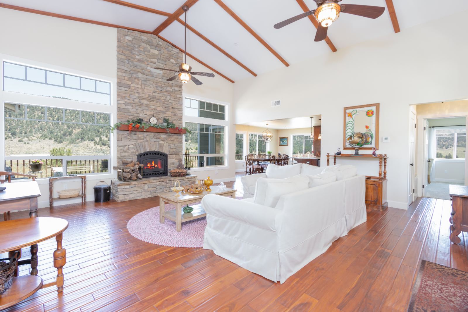 Great room with stone fireplace, vaulted beams and valley windows