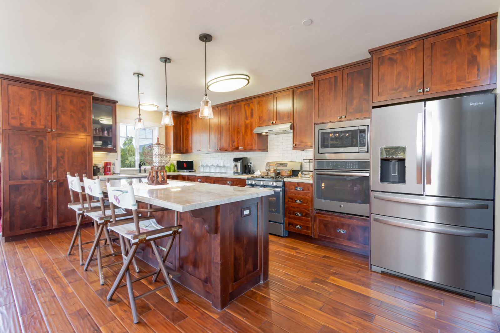 Kitchen with cherry cabinets, marble island and stainless appliances