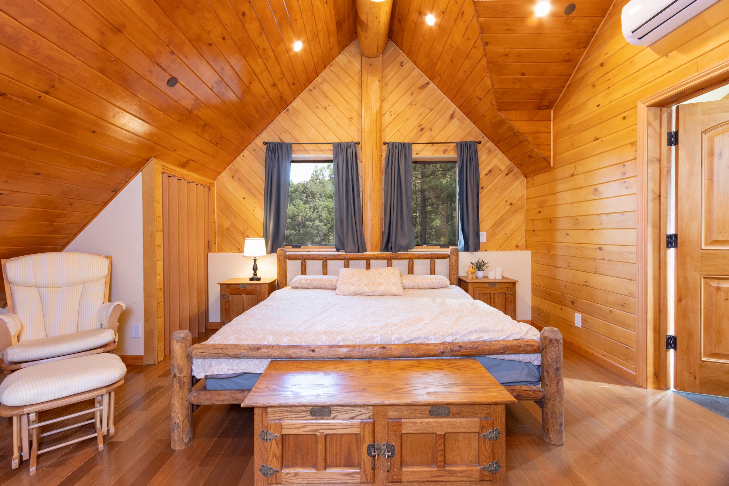 Pine-paneled bedroom with a log bed and vaulted ceiling