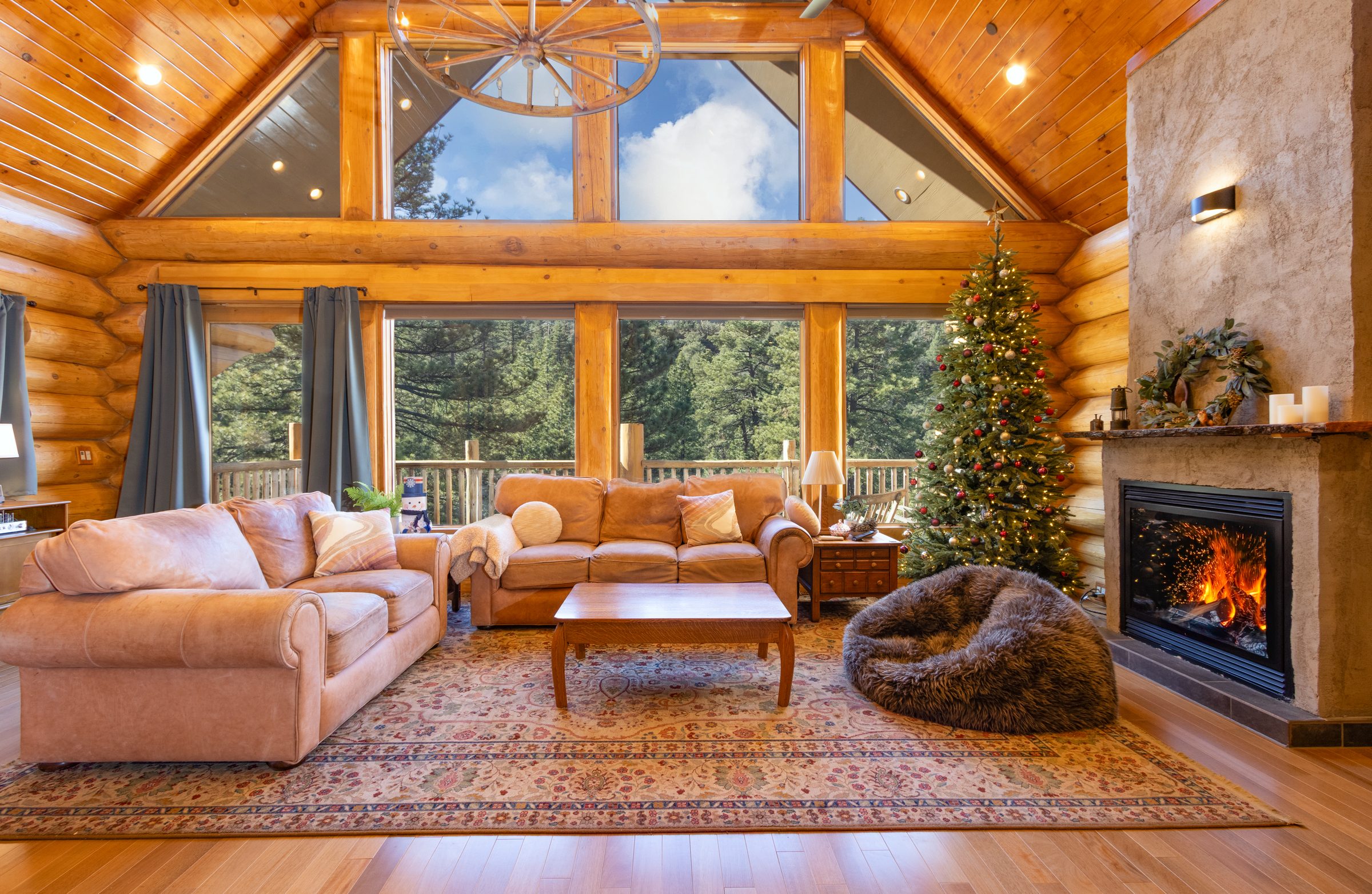 Log great room with a wall of windows and a stone fireplace