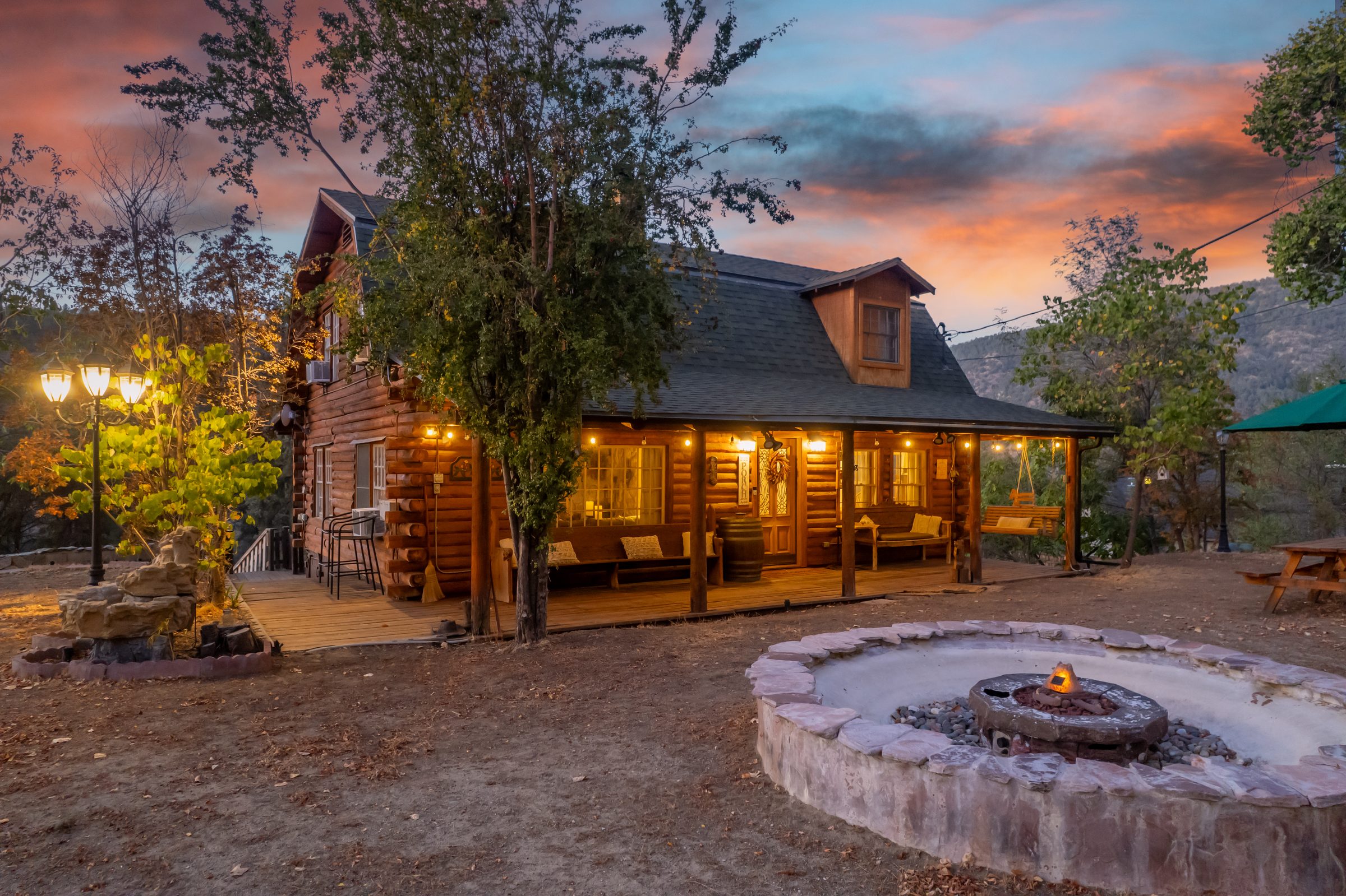 Log cabin glowing at twilight with a lit fire pit, Frazier Park
