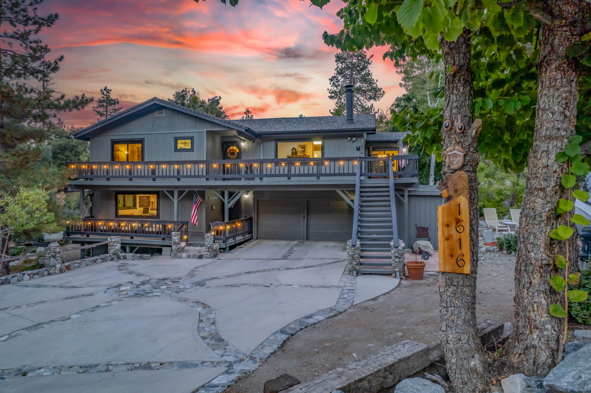 Front of a mountain home at twilight, deck lights glowing